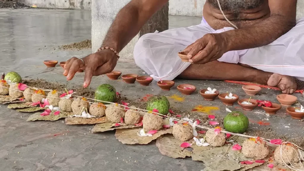 A man performs the sacred Pind Daan, offering rice balls (pindas) and flowers to honor his ancestors- Dispose Shradh materials home