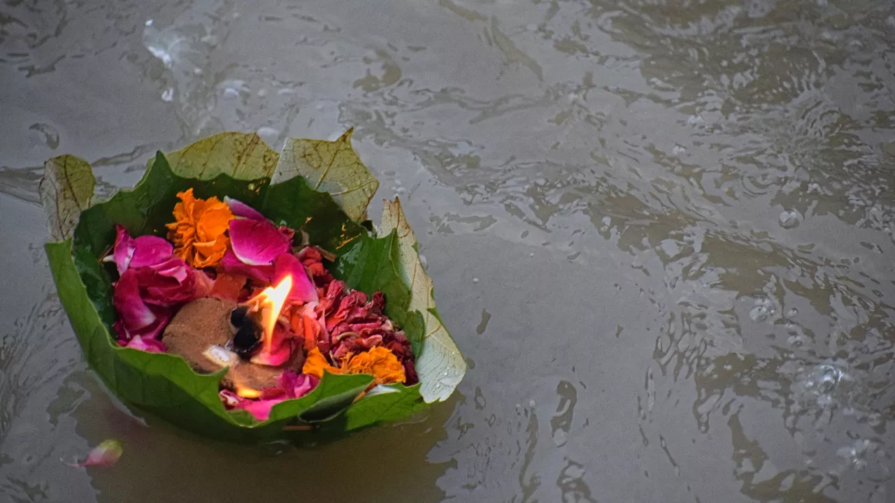 Image of a diya in leaf and move towards by flow of river- Rivers sacred for Pitrupaksha